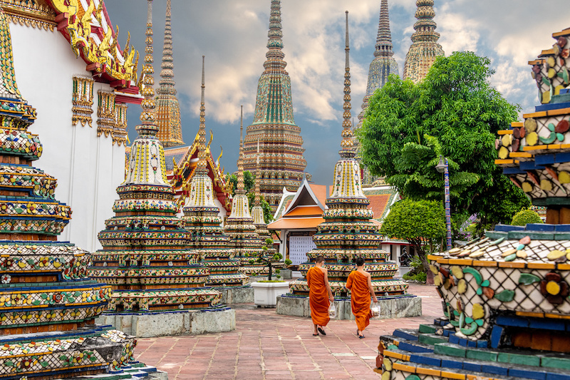 Two monks walking alongside stupas at the Wat Pho Temple in Bangkok