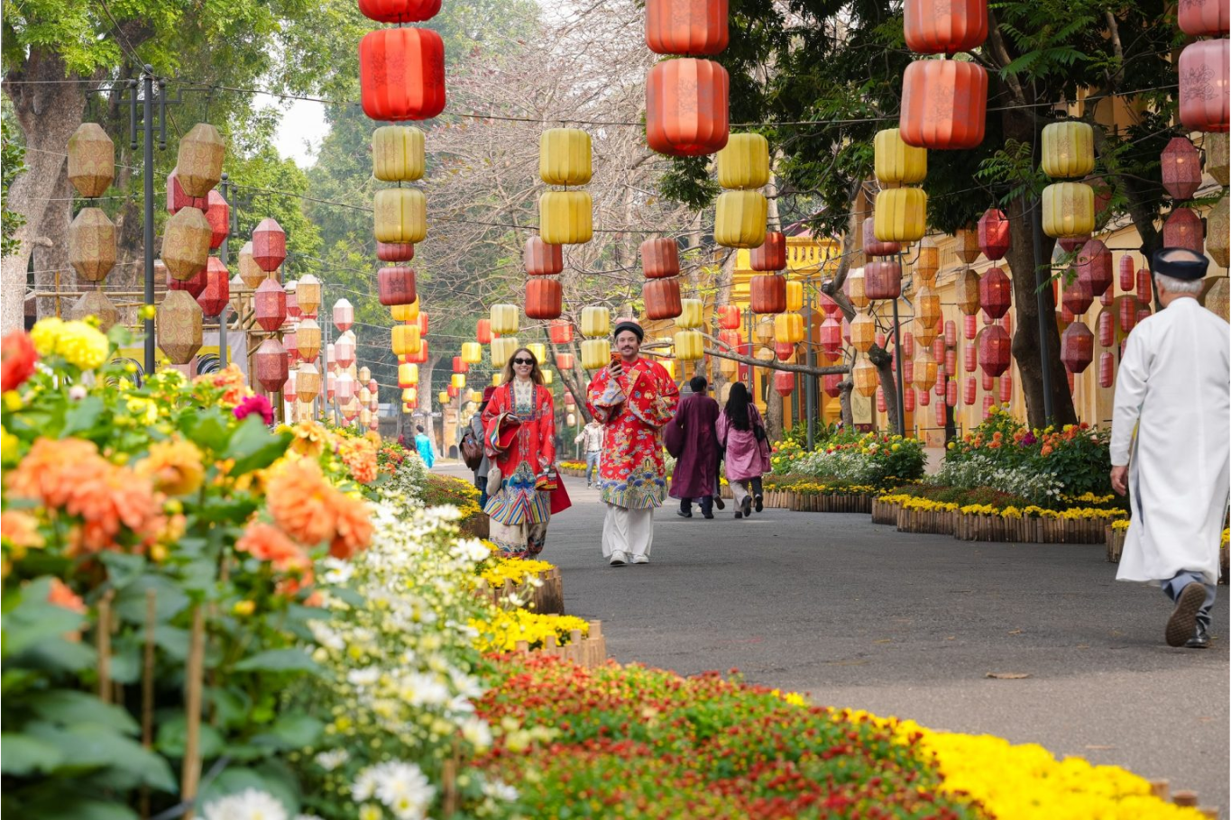 Visitors wearing traditional Vietnamese costumes while walking through a decorated heritage area in Hanoi.