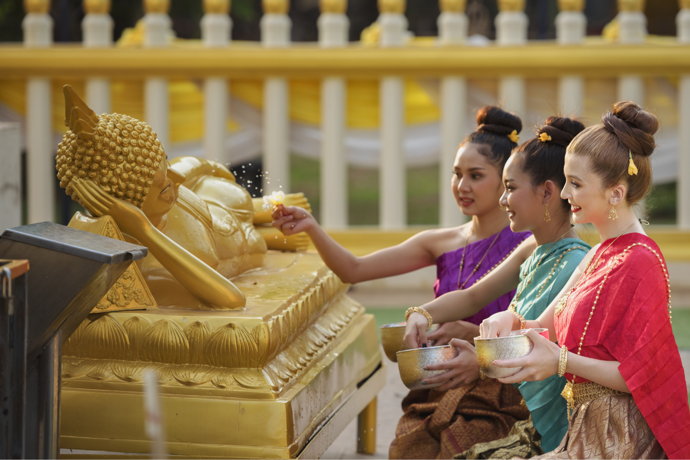 Thai women performing the traditional Buddha bathing ritual during Songkran, one of the most meaningful Southeast Asian festivals.