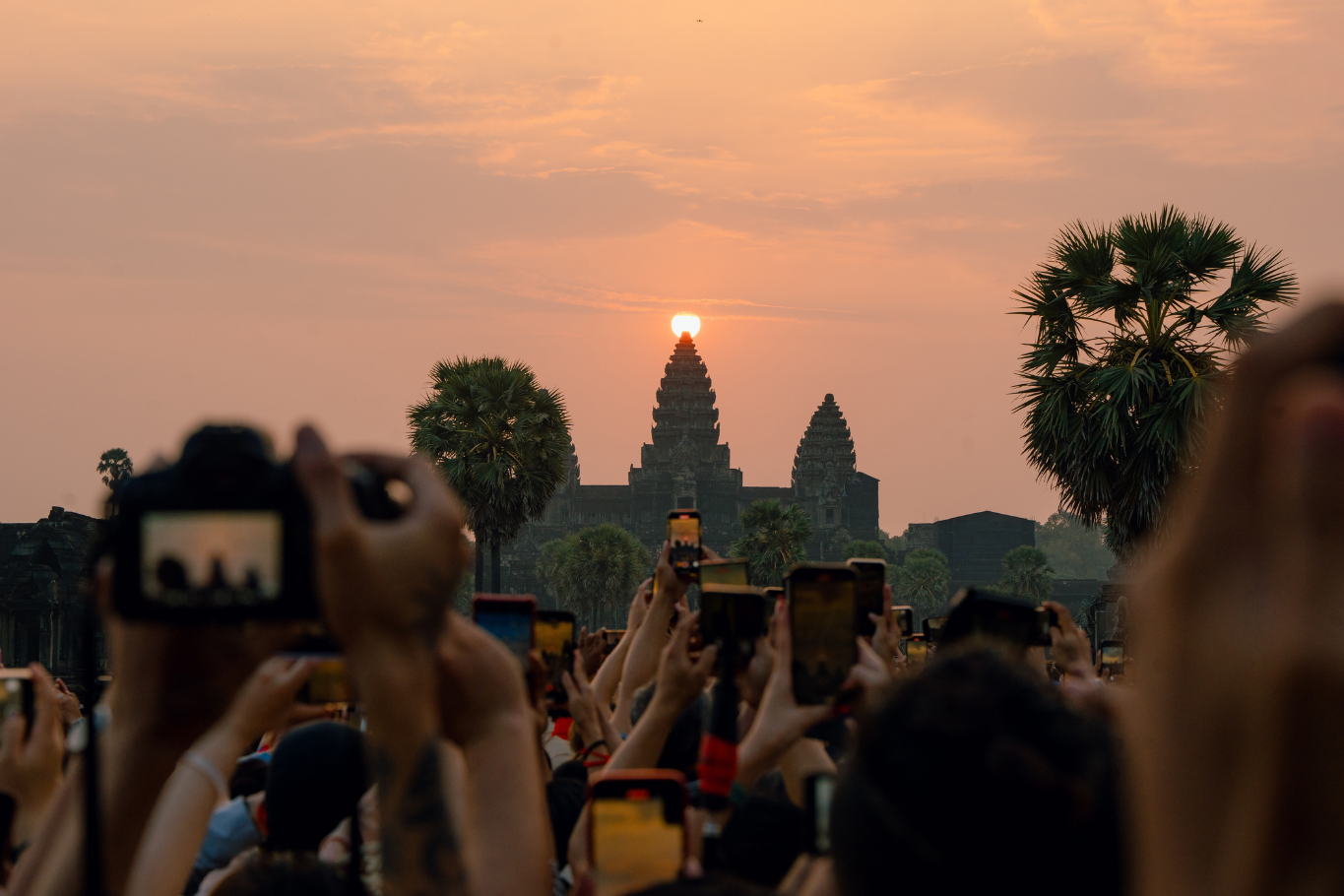 Crowd photographing the golden sunrise directly behind the towers of Angkor Wat.
