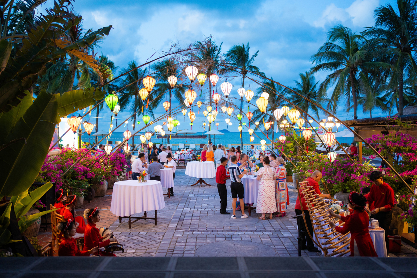 Guests enjoying an outdoor evening cocktail reception under illuminated silk lanterns at a resort