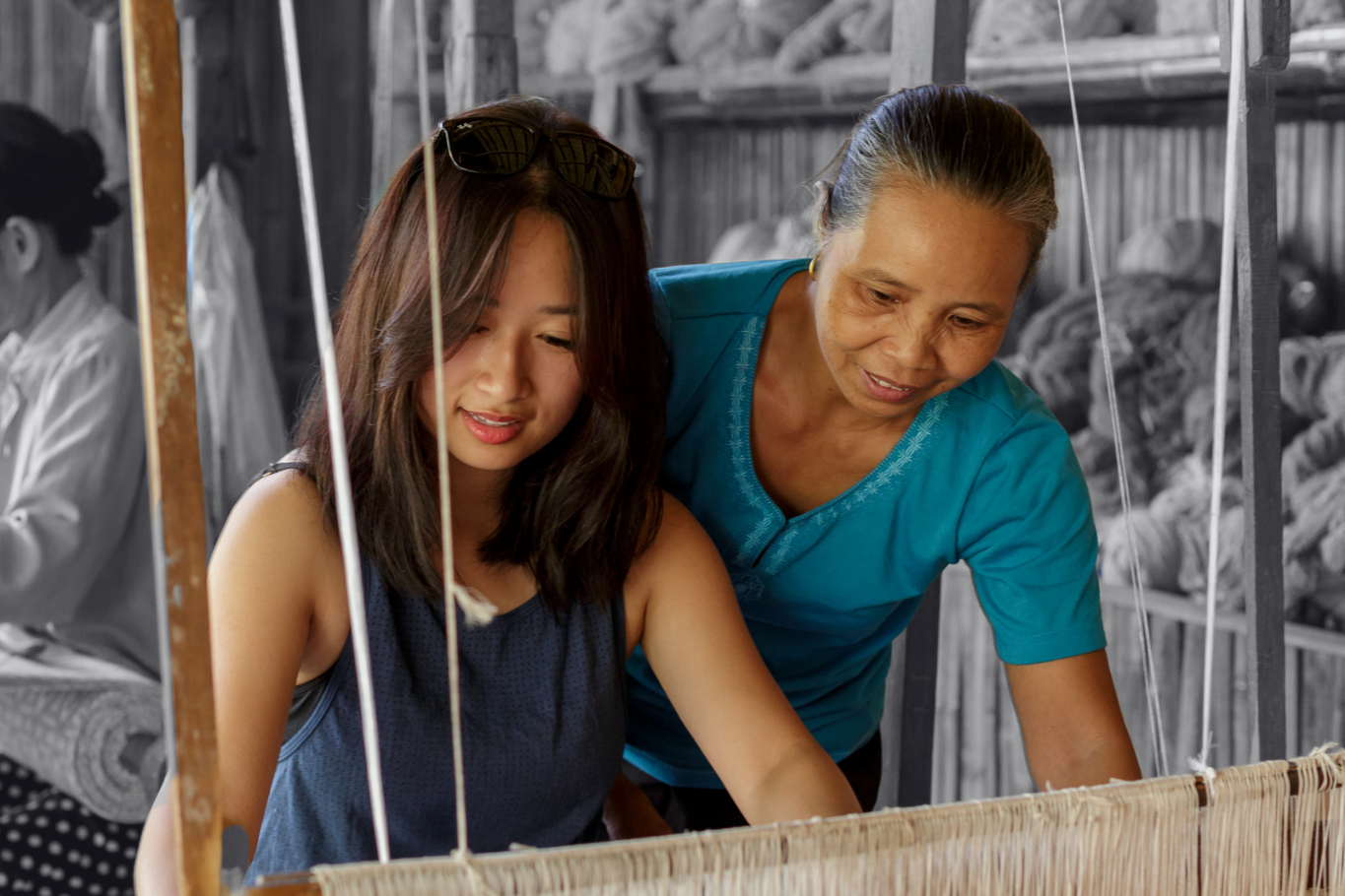 Young girl learning traditional loom weaving from a local female artisan.