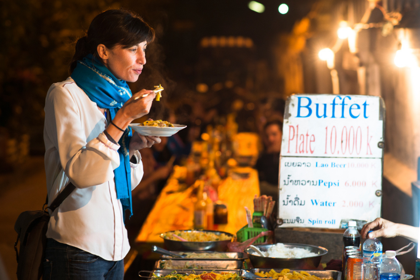 Enjoy a plate of food at an outdoor night market buffet stand in Laos